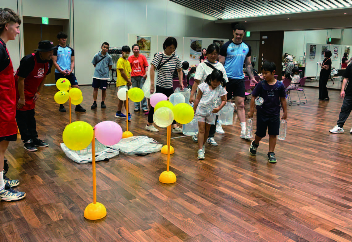 子どもたちはラグビー選手と一緒に水の運搬作業を体験